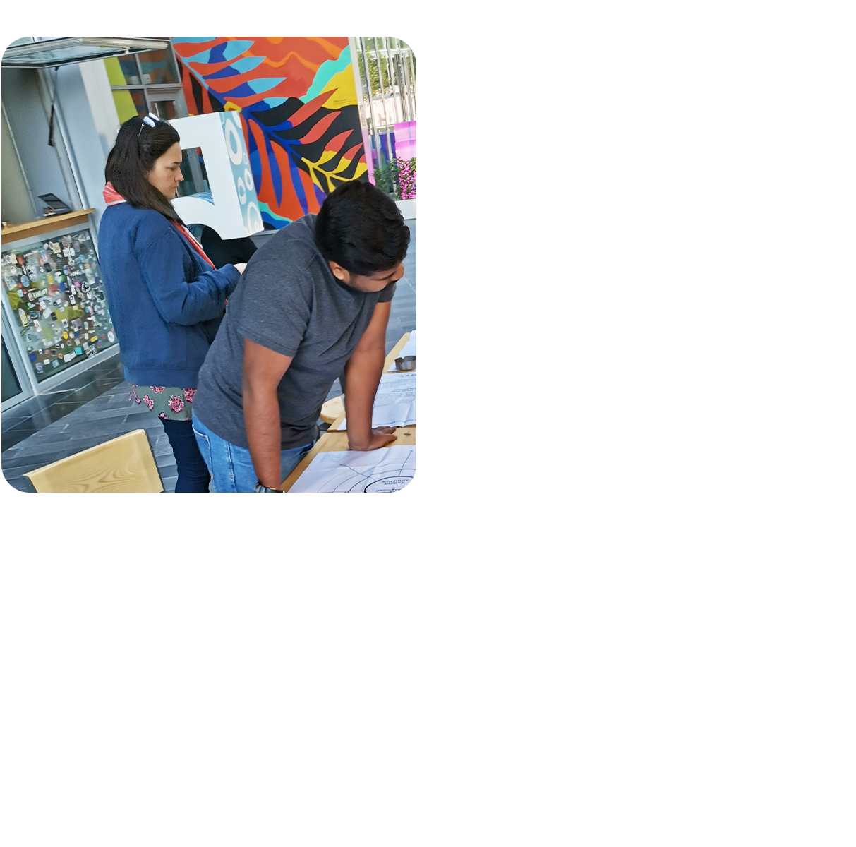 A group of people engaged in a table top activity, in an outdoor workspace.