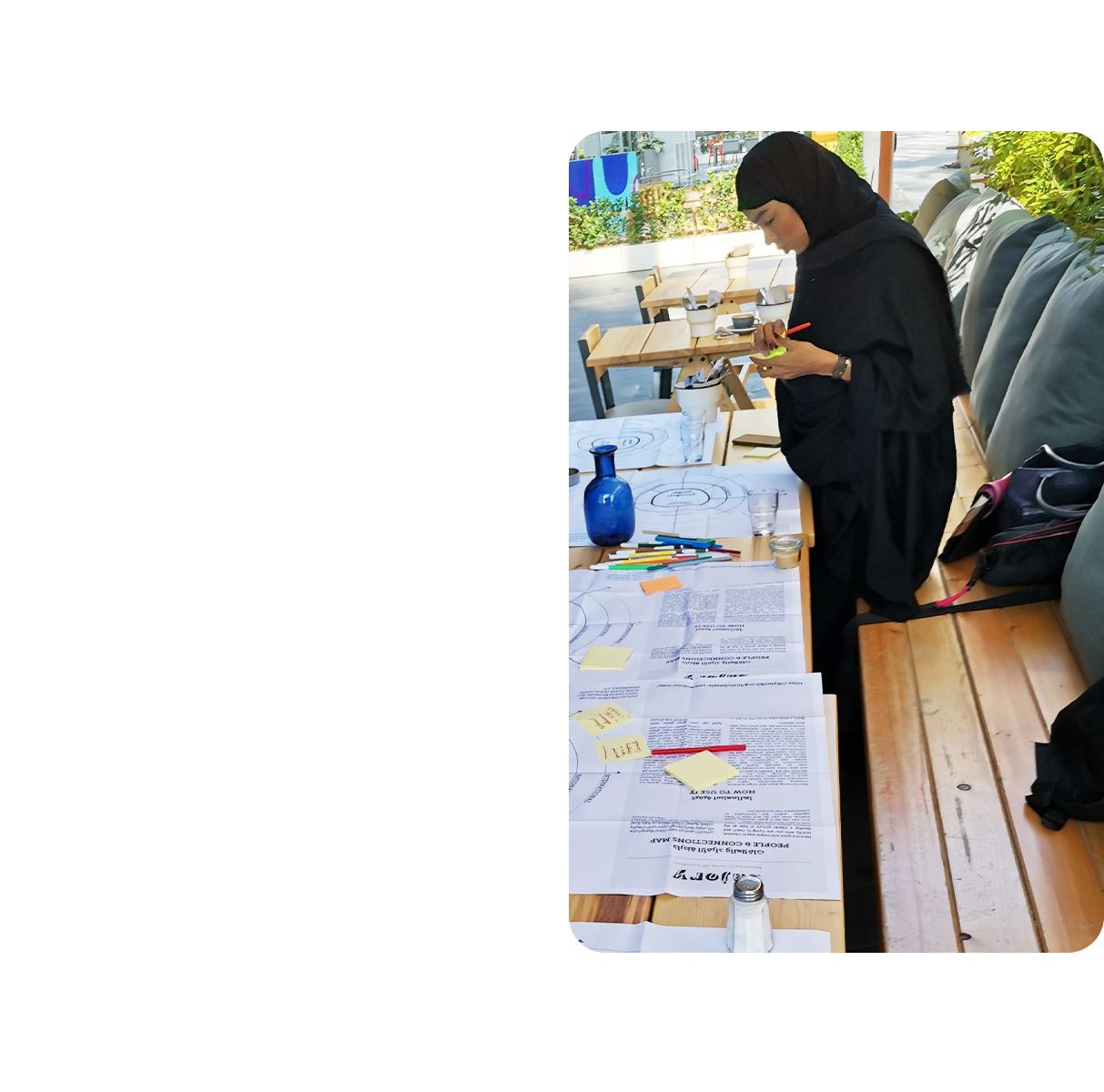 A group of people engaged in a table top activity, in an outdoor workspace.